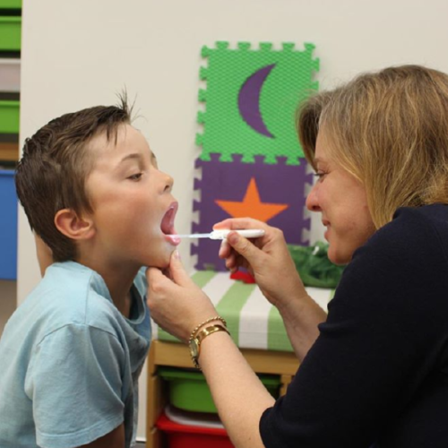 Speech-Language Pathologist (SLP) Using Throat Scope Illuminating Tongue Depressor with Child